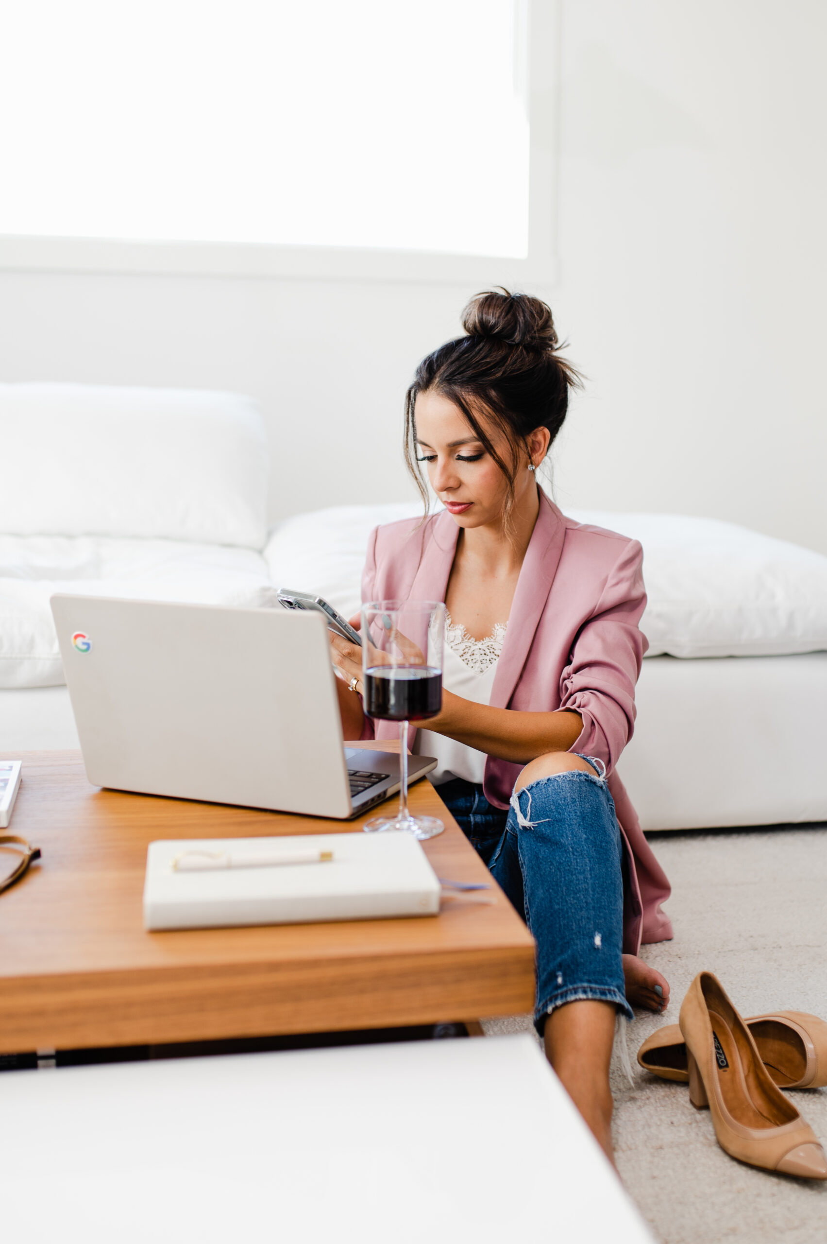 Content creator sitting on the floor with a laptop and phone, brainstorming Instagram inspiration to overcome creative block and stay consistent.